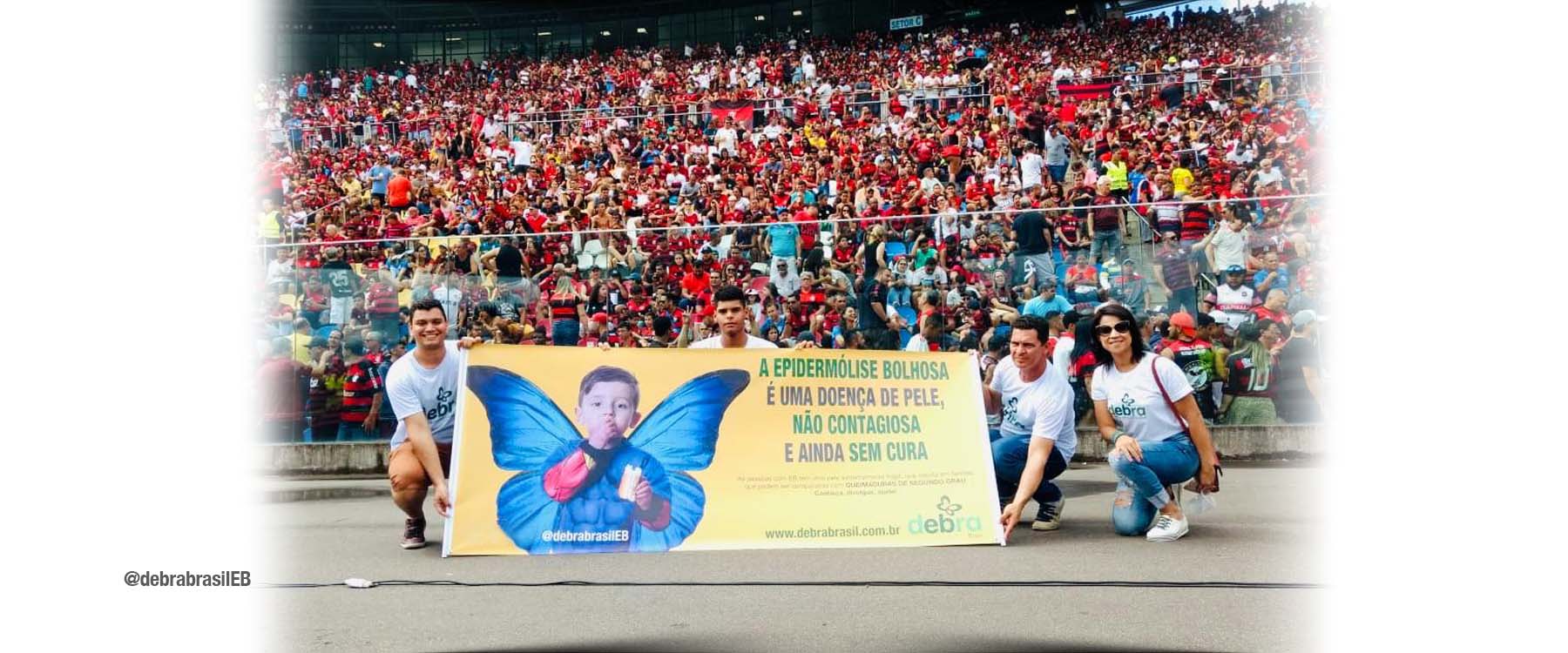 Faixa da DEBRA Brasil sobre a epidermólise bolhosa (EB) em um estádio de futebol lotado