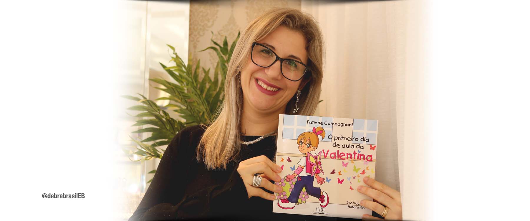 Tatiane Compagnoni, mãe da bebê Valentina que nasceu com epidermólise bolhosa (EB) distrófica recessiva, segura o livro que ela escreveu “O primeiro dia de aula da Valentina”