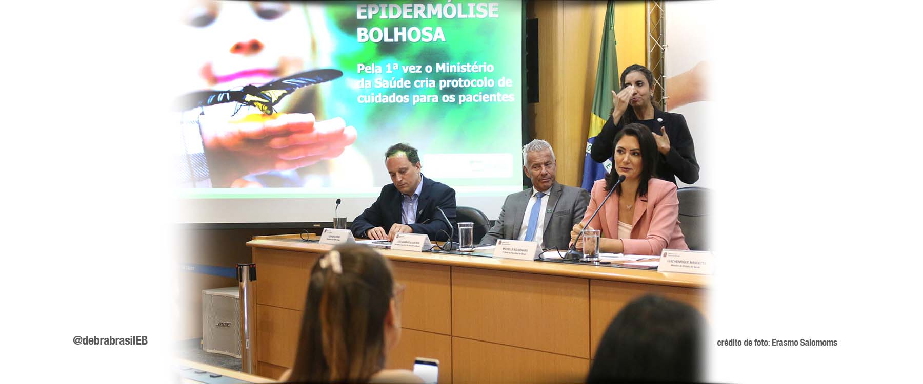 O presidente da DEBRA fazendo anotações enquanto a primeira-dama, Michelle Bolsonaro, fala no microfone no lançamento da consulta pública do PCDT epidermólise bolhosa (EB)