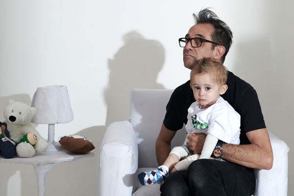 Márcio Rodrigues, fotógrafo da Lumini e fotógrafo voluntário da DEBRA Brasil, sentado com o Theo, bebê com epidermólise bolhosa (EB) 